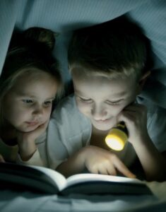 kids with flash light reading book