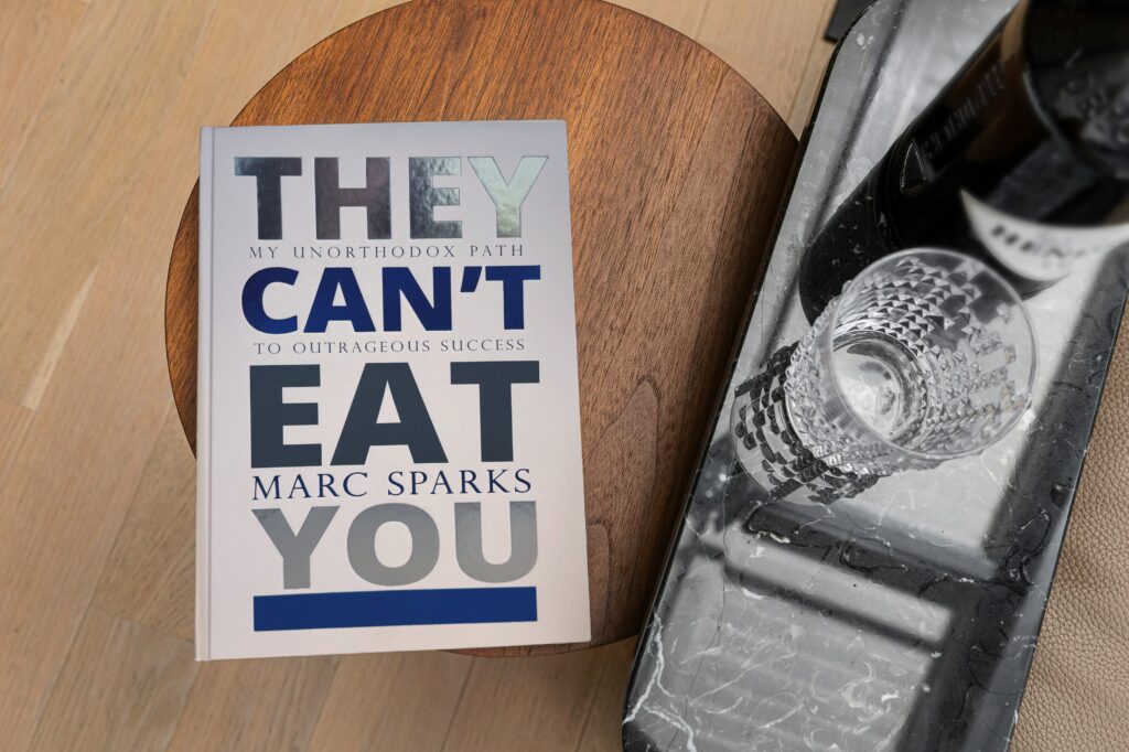 A copy of “They Can’t Eat You” by Marc Sparks on a table next to a bottle and glass