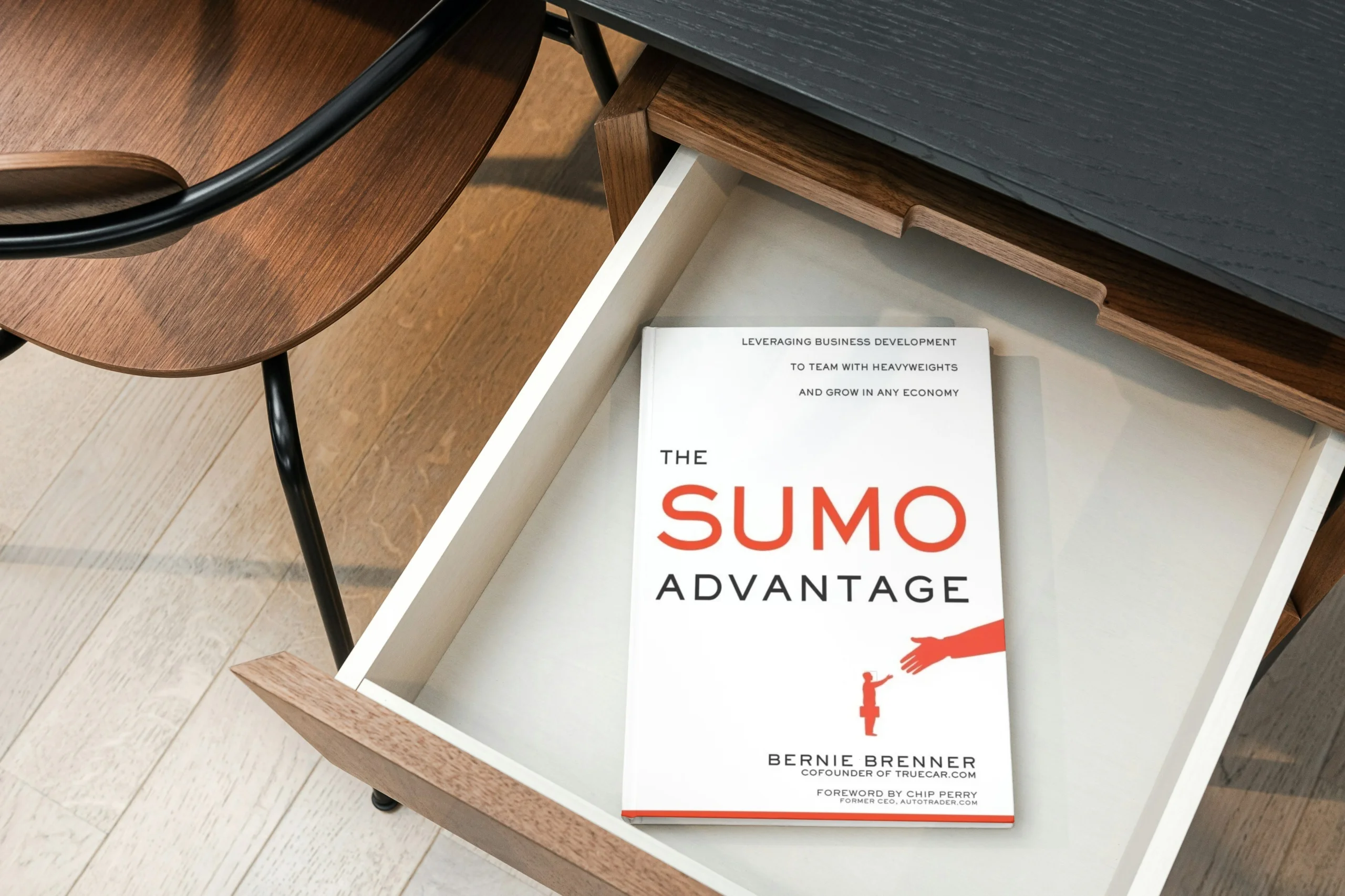 A copy of “The Sumo Advantage” by Bernie Brenner, with a white cover featuring a small business person shaking hands with a large hand